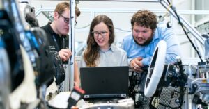 Engineers collaborating on a car project in a modern automotive workshop using advanced technology.